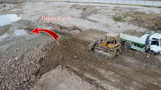 Pouring soil to delete pond process by Dozer D37 with dump trucks unloading