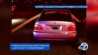 Firefighters run hose through car parked in front of hydrant