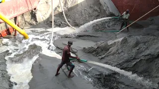 Sand is being unloaded from large ships with powerful dredger machines