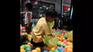 James playing inside a trampoline with balls