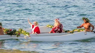 Santa and Mrs. Claus arrive in Maui, Hawaii in an outrigger canoe at Fairmont Kea Lani