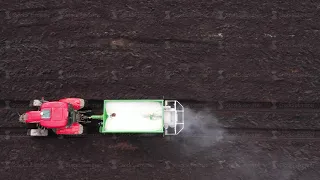 Tractor spreads dry mineral fertilizers on a field.