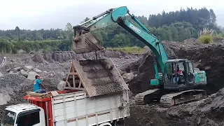 excavator working to dredge and load sand into the truck bed - 4k