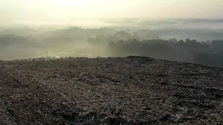 Съемка с дрона городской свалки. Видео квадрокоптера с высоты птичьего полета над кучей мусора.