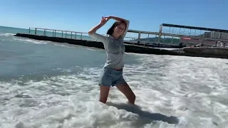 Denim shorts and a gray ribbed sweater in the sea gets wet