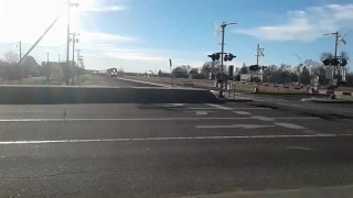 GUY ON BICYCLE GOES AROUND GATES IN FRONT OF BNSF TRAIN