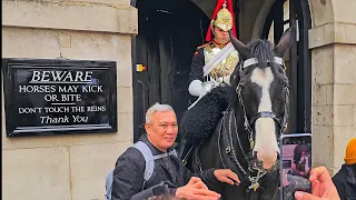 DISRESPECTFUL IDIOT TOURIST HOLDS THE REINS and grins like it's his horse at Horse Guards!