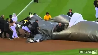 Baseball grounds crew member blown across field in tarp from severe winds.