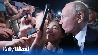 Putin ambushed as he poses for selfies with residents and kisses fans