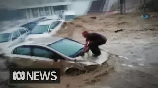 Man 'surfs' his car bonnet to escape as flash floods hit Turkish capital | ABC News