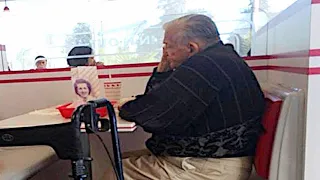 Kellnerin nimmt altem Mann Besteck aus der Hand, ohne zu ahnen, wer ein Foto davon macht