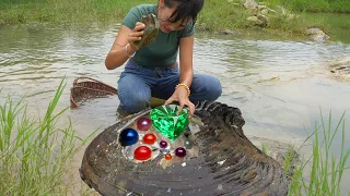 The girl caught a big clam in the river and smashed it open with a stone to discover precious pearls