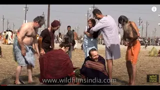 Western sadhus watch as Naga Sadhu applies human cremation ash on his body : Kumbh Mela, Allahabad