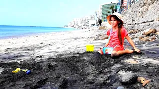 Дети играют с черным песком на пляже. Ринка и Саминка