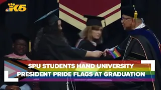 SPU students hand university president pride flags instead of shaking his hand at graduation