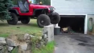 Jeep crawls off of cement wall.