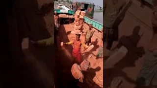 African worker loading and transporting 28 Bricks on his head.