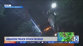 Amazon truck stuck in mud, threatens homes below