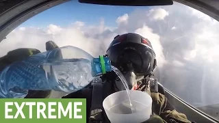 Fighter jet pilot drinks water cup while flying upside down