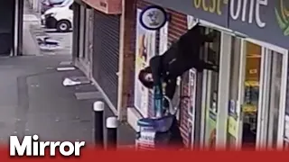 Elderly woman lifted off her feet by shop shutters