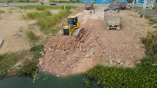 Great job Action Making Road Cross the Water By Dozer Pushing Stone with Dump Truck Unloading Stone