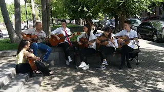 Yerevan, Armenia, June 2022. Guitar students playing with their teacher in the street (1)
