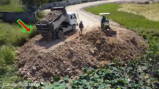 Building road across the lake by Komatsu dozer with dump trucks unloading