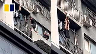 Heroic man holds up child dangling from balcony