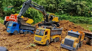Volvo controlled excavator scoops soil onto large trucks, RC vehicles transport construction soil