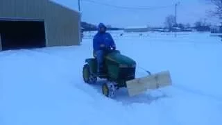 Plowing snow with homemade snow plow for lawnmower