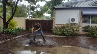 Plumber clearing a blocked grate after storm