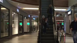 Женщина с ребёнком идёт вниз по эскалатору, который движется вверх