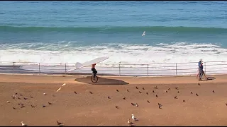 Unicyclist carrying airplane wing in Pacifica, CA.