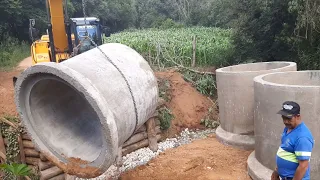 Escavadeira hidraulica tirando ponte e colocando tubos( Excavator removing bridge and placing pipes)