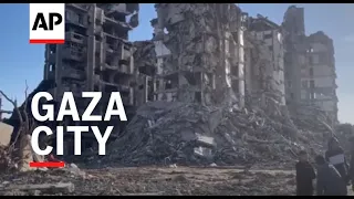 Palestinians walk among destroyed buildings in neighbourhoods in Gaza City, amid scenes of devastati