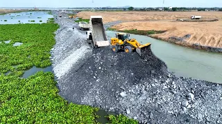 Constructing Water-Based Highway WheelLoader effortlessly rolls big stone to water , truck spreading