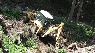 New Holland LB 115.B backhoe digging in the forest