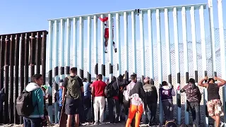 Immigrants climb over U.S. Mexico border wall