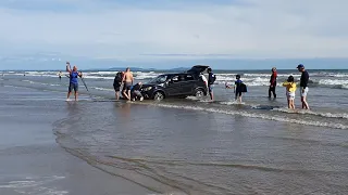 Car stuck on beach as tide come in.