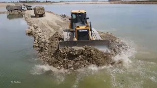 Incredible dike building across the lake mighty bulldozer push spreading soil and truck unload soil