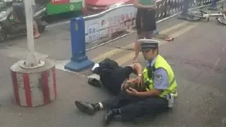 Officer directing traffic sitting on the ground? He's also taking care of the wounded