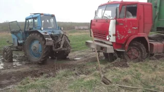 Russian MTZ-82 tractor gets up for the buck trying to pull out a truck