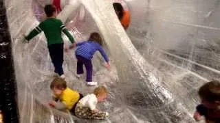 Katy and kiddos playing in TapeScape - a play area made entirely of packing tape on a frame.