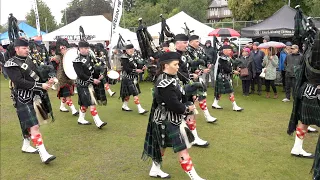 Lonach Pipe Band march off playing Cock o' the North in pouring rain at 2023 Aboyne Highland Games