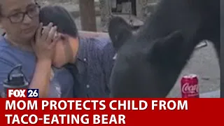 Mother shields son from bear on table eating tacos