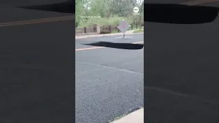 Bystanders watch as large sinkhole swallows portion of Colorado road