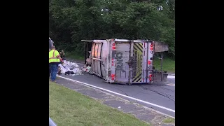 Trash truck rolls over, spills debris all over road