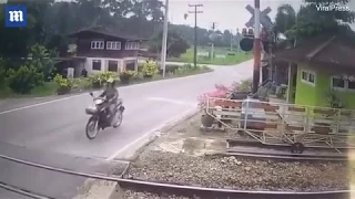 Dramatic moment a woman motorcyclist was knocked off her motorbike by a level crossing barrier