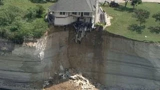 Couple looks on as house falls off cliff