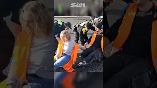 Police use roller boards to roll glued together eco-protesters from road